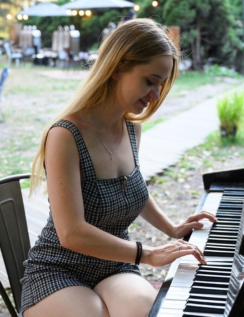 Girl playing the piano in a skirt and low cut crop showing cleavage